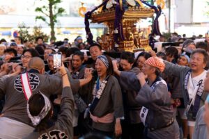 Excited crowd carrying a traditional mikoshi portable shrine during a Japanese festival