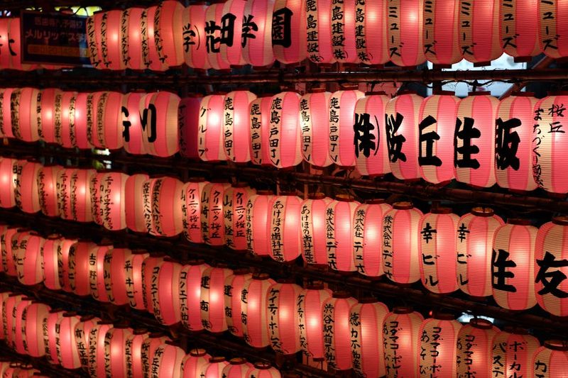Brightly lit paper lanterns displaying Japanese characters at a night festival in Tokyo