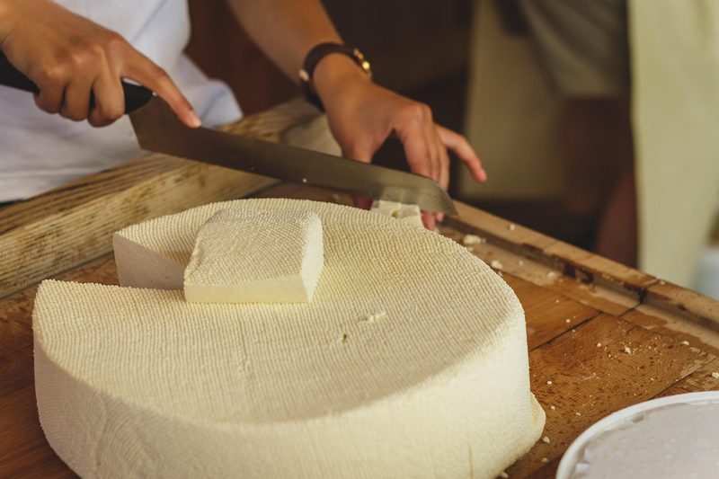 Artisan cheese wheels aging on wooden shelves in a dairy factory