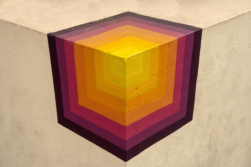 Vibrant geometric mural painted on a wall creating an optical illusion effect