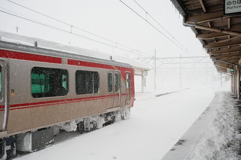 Train departing from a snow-covered station platform in Japan