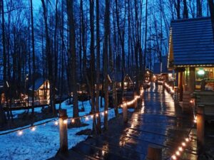 Magical evening scene of illuminated log cabin craft shops at Ningle Terrace in Furano